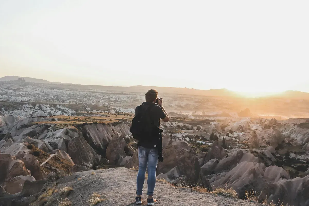 Blog podróżniczy — A photographer stands on a cliff capturing the stunning suns